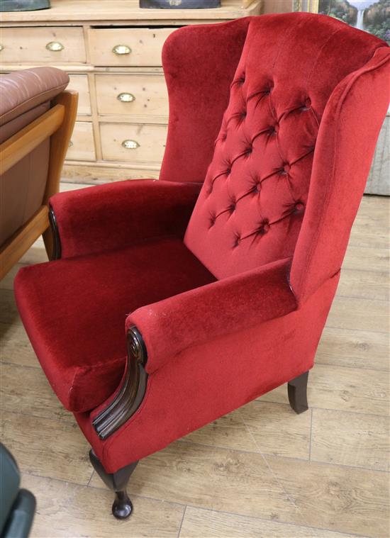 A wing armchair with buttoned red velour upholstery